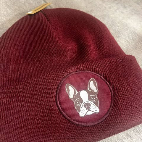 A red beanie hat with a patch of a dog's face on the front.