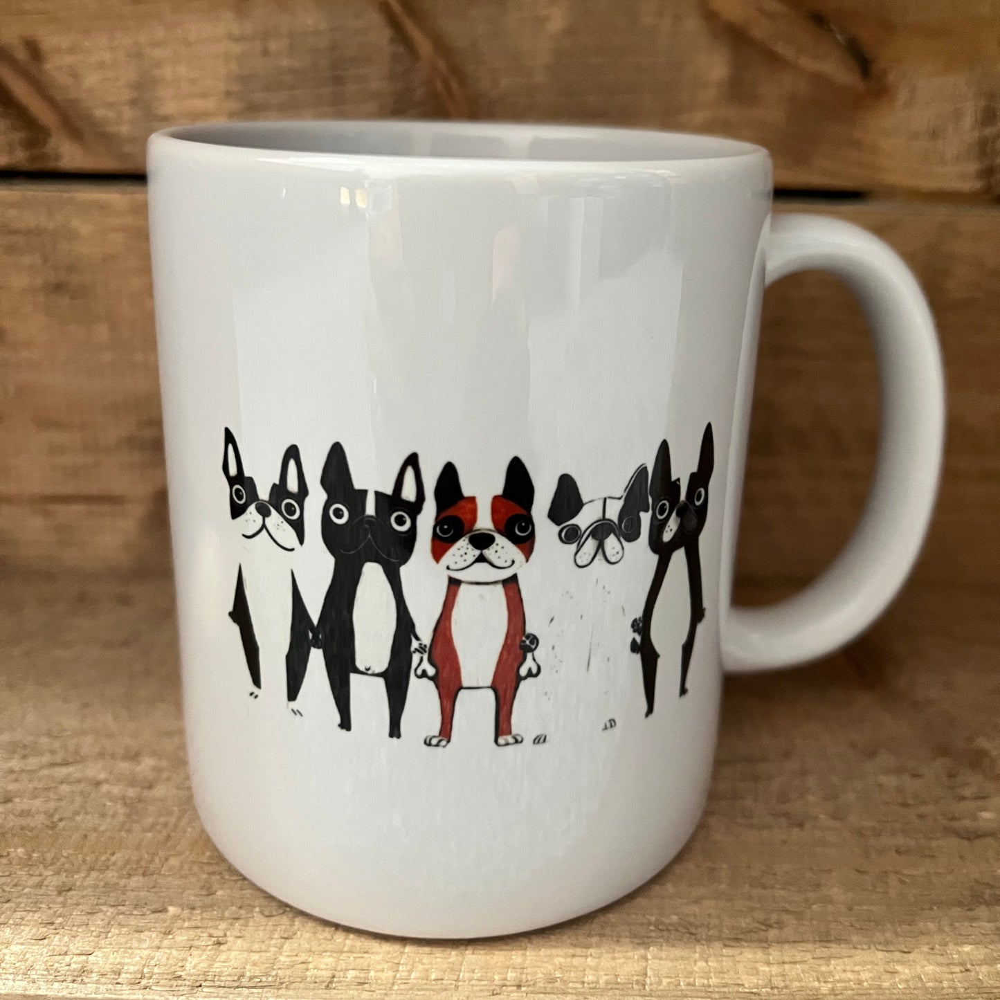 White mug with black illustrations of dogs on a wooden surface