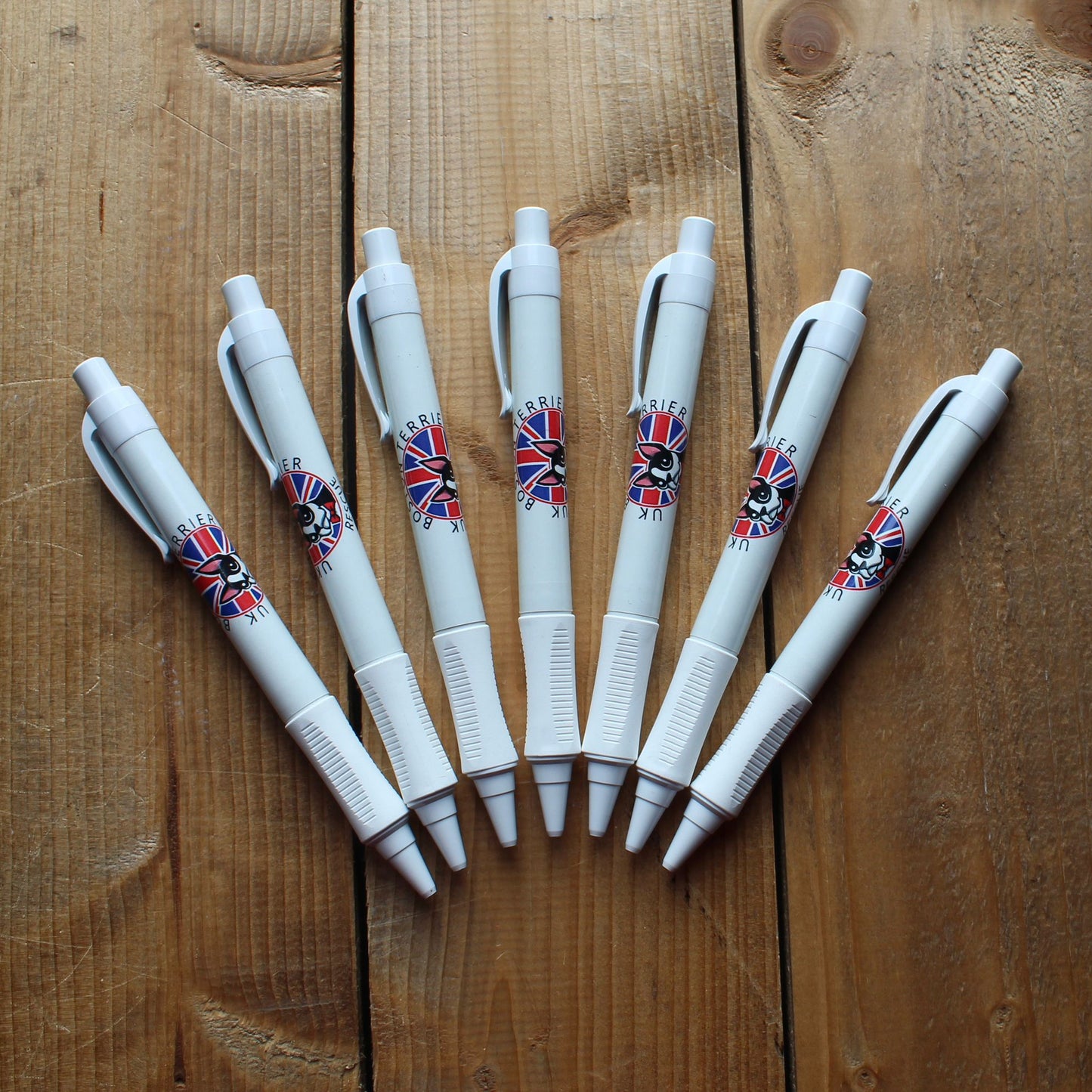 White pens with British flag designs on a wooden surface