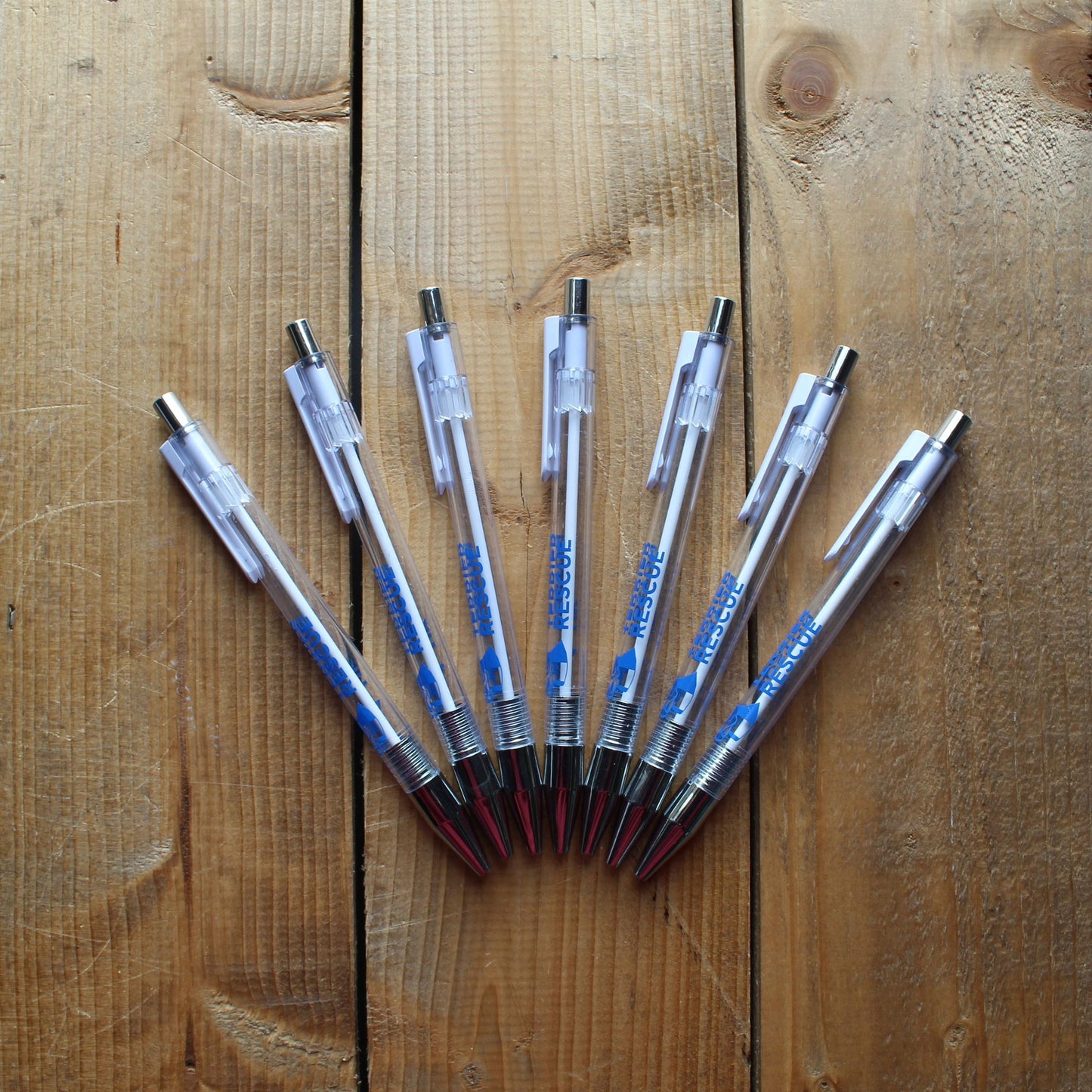 Assorted pens arranged on a wooden surface